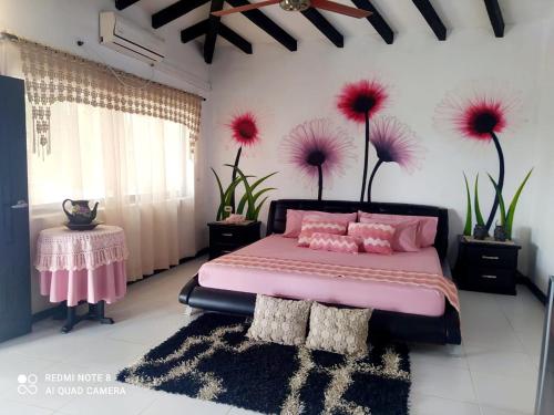 Un dormitorio con una cama rosa y flores en la pared en Casa Campo Emaus en Caucasia