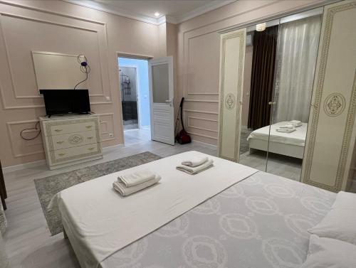 a white bedroom with a bed and a mirror at Караван Сарай 3 in Türkistan