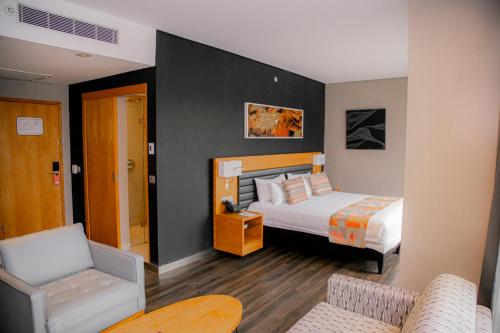 um quarto de hotel com uma cama e uma cadeira em Ubumwe Grande Hotel em Kigali