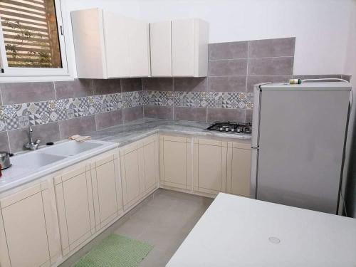 a kitchen with white cabinets and a white refrigerator at Maison a louer à kelibia in Kelibia