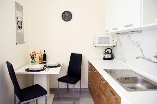 een kleine keuken met een wastafel en een tafel met stoelen bij Apartment with a sun terrace,privat parking in Banská Bystrica
