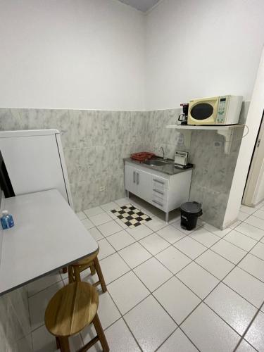 a kitchen with a white tiled floor with a table and chairs at Kitnets da Lane in Campos do Jordão