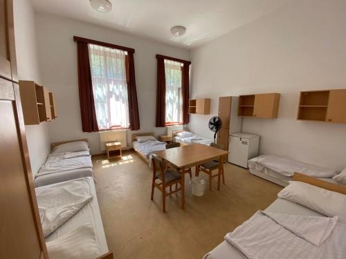 a room with several beds and a table and a room with a group at Sio Hostel in Siófok