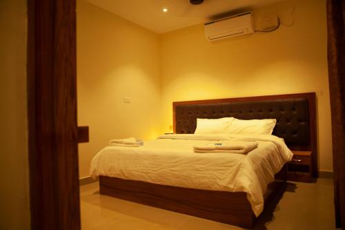 a bedroom with a large bed with white sheets at WESTN Resorts in Kuttālam