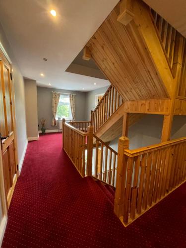 a hallway with a wooden staircase with red carpet at Deerbrook House B&B in Cahir
