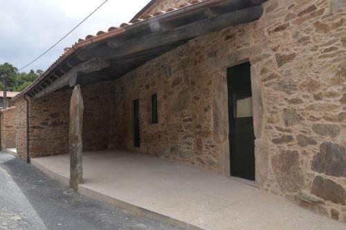 ein Steingebäude mit einer großen Terrasse in der Unterkunft Casa Peón de Pardaces in Santiago de Compostela