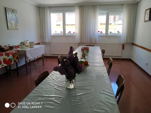 uma mesa longa com um vaso de flores sobre ela em Albergue La Esperanza de la Sagrada Familia em Melgar de Fernamental