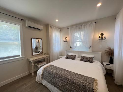 1 dormitorio con cama blanca y espejo en The Reminisce vacation home 5br/3bt,downtown BH, en Bar Harbor