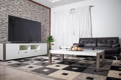 a living room with a black leather couch and a tv at luxury suites CHESTER ONE in Dakar