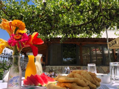 einen Tisch mit einem Teller Essen und Blumen darauf in der Unterkunft Hotel Apostoli in Përmet