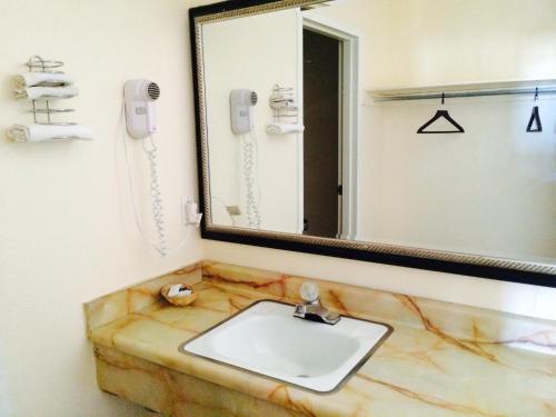 La salle de bains est pourvue d'un lavabo en marbre et d'un miroir. dans l'établissement Regal Inn Las Vegas New Mexico, à Las Vegas