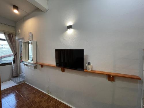 a flat screen tv sitting on a shelf on a wall at Acozyposhtel in Bangkok