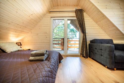 sypialnia z łóżkiem, kanapą i oknem w obiekcie Domki Miśków w mieście Międzyzdroje