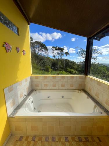 a large tub in a room with a large window at Chalés de Triunfo in Triunfo