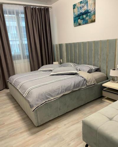 a bedroom with a large bed with a green headboard at Metamorfoz Apartment in Mamaia Nord