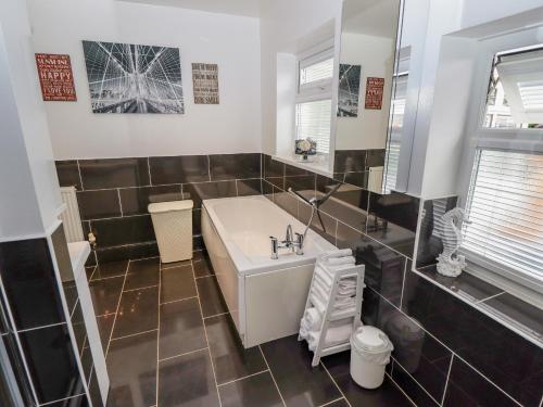 a bathroom with a white sink and black tiles at Hallstead in Skegness