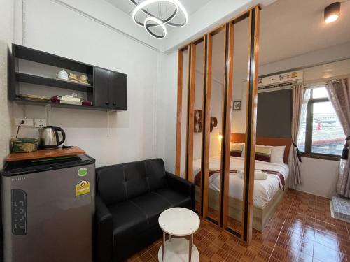 a small room with a bed and a couch in it at Acozyposhtel in Bangkok