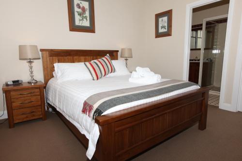 a bedroom with a large bed with white sheets and a night stand at House on the Hill Bed and Breakfast in Huonville