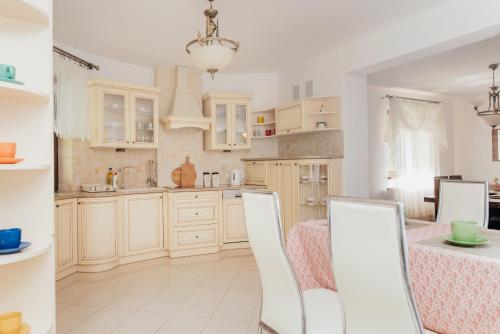 a kitchen with white cabinets and a table and chairs at Zarabie Residence in Myślenice