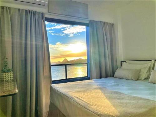 a bedroom with a large window with a view of the ocean at Hotel Espadarte in Iriri