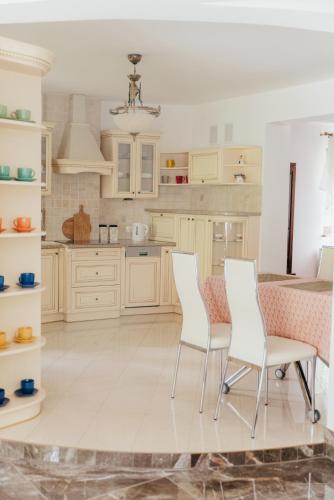 a kitchen with white cabinets and a table and chairs at Zarabie Residence in Myślenice