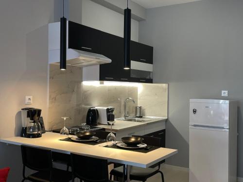 eine Küche mit schwarzen Schränken und einem weißen Kühlschrank in der Unterkunft Modern Apartment 305 in Xánthi