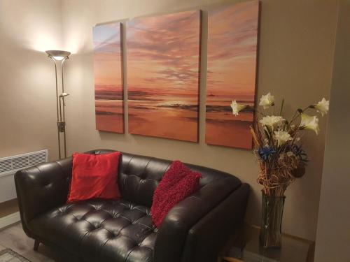 a living room with a leather couch and a vase with flowers at The Savile - Luxury Apartment Leeds - Your Next Stay in Leeds