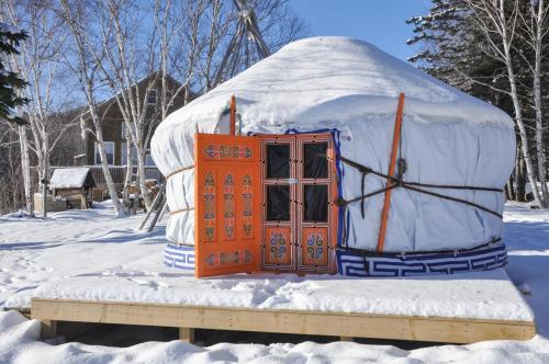 a yurt with an orange door in the snow at Cabot Shores in Indian Brook