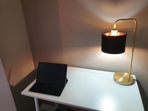a laptop computer sitting on a white desk with a lamp at The Savile - Luxury Apartment Leeds - Your Next Stay in Leeds