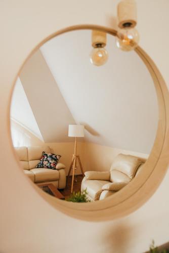 a mirror reflecting a living room with a couch at Zarabie Residence in Myślenice