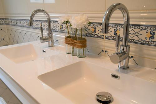 two sinks in a white kitchen with two faucets at Maison Marguerite in Bordères-Louron