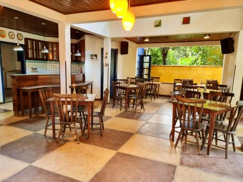 um restaurante com mesas e cadeiras de madeira numa sala em Pousada Rumo dos Ventos em Paraty