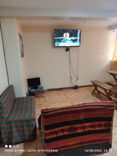 sala de estar con sofá y TV en la pared en Anacondor Tours & House en Cusco