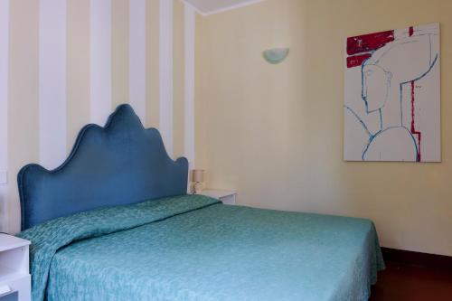 a bedroom with a blue bed and a painting on the wall at Hotel Club i Pini - Residenza d'Epoca in Versilia in Lido di Camaiore