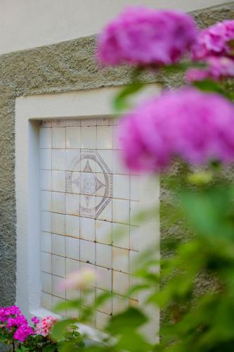 a window with an eye on the side of a building with purple flowers at Hotel Club i Pini - Residenza d'Epoca in Versilia in Lido di Camaiore
