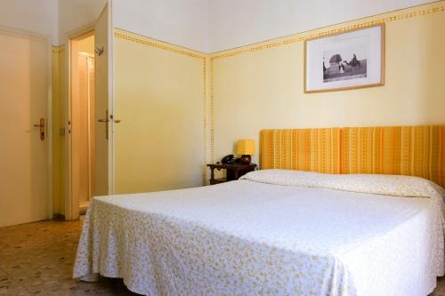 a bedroom with a white bed with an orange headboard at Hotel Club i Pini - Residenza d'Epoca in Versilia in Lido di Camaiore