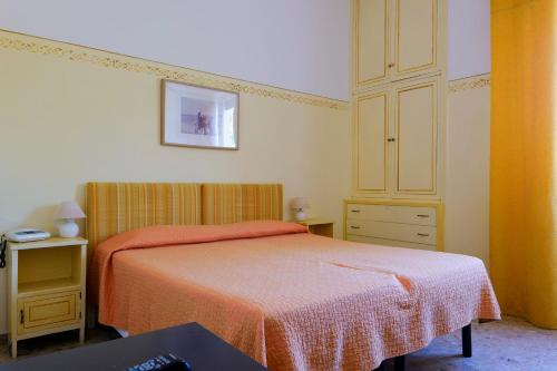 a bedroom with a bed with an orange blanket and a dresser at Hotel Club i Pini - Residenza d'Epoca in Versilia in Lido di Camaiore