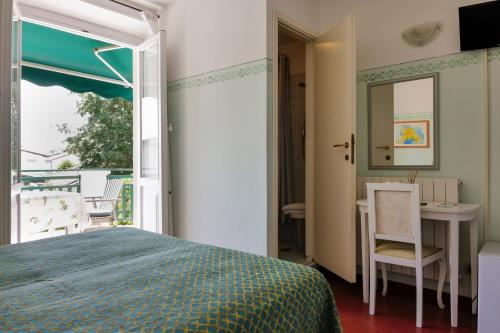 a bedroom with a bed and a table and a window at Hotel Club i Pini - Residenza d'Epoca in Versilia in Lido di Camaiore