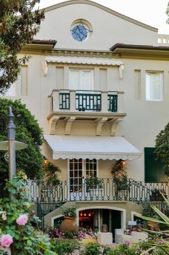 a building with a balcony with a clock on it at Hotel Club i Pini - Residenza d'Epoca in Versilia in Lido di Camaiore