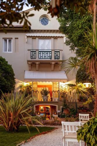 a white house with a clock on top of it at Hotel Club i Pini - Residenza d'Epoca in Versilia in Lido di Camaiore