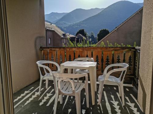 a white table and chairs on a balcony with mountains at Appartement T3 dans résidence 6 pers in Juzet-de-Luchon