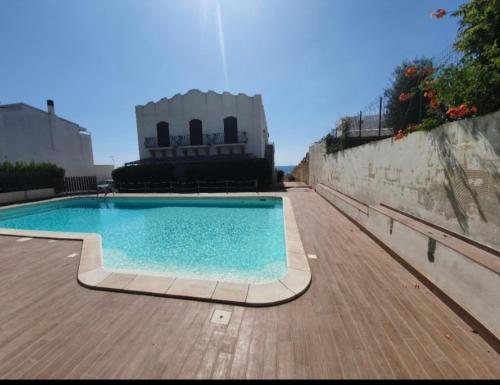 a swimming pool on a wooden deck next to a wall at La riva in Noto Marina