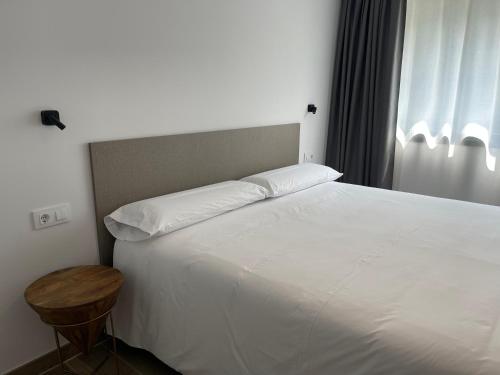 a bedroom with a large white bed and a table at APARTAMENTOS TURÍSTICOS EL RINCONÍN in Llanes