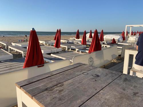 - une table et des chaises avec des parasols rouges sur une plage dans l'établissement Grand rez de jardin-terrasse avec vue sur la mer - 2 chambres, à Blonville-sur-Mer