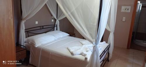 a bedroom with a canopy bed with white sheets at Savvas Studios in Kefalos