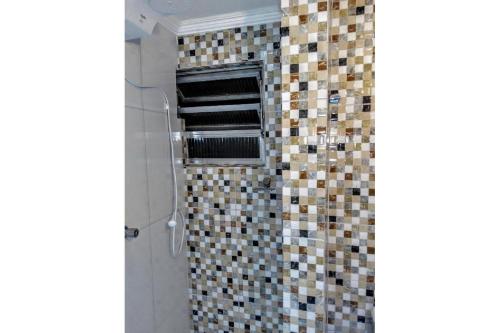 a bathroom with a shower with mosaic tiles on the wall at Apartamento Primeira Quadra Da Praia in Praia Grande