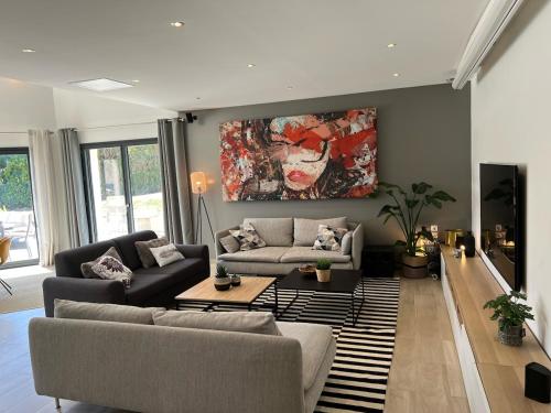 a living room with two couches and a painting on the wall at L’escale du Roy : maison récente proche versailles in La Queue-lès-Yvelines