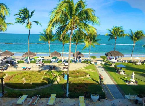 uma vista para um resort com palmeiras e o oceano em FLATS VISTA MAR e FRENTE MAR NA PRAIA DOS CARNEIROS em Praia dos Carneiros