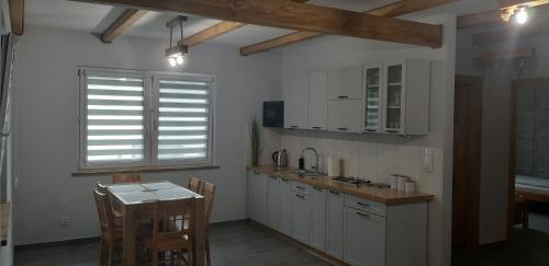 a kitchen with white cabinets and a table in it at przy lesie in Białowieża