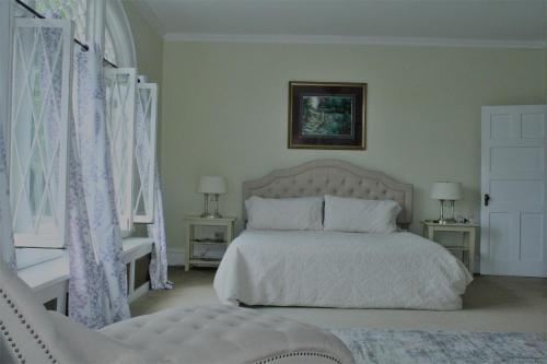 Franklin Manor Bed and Breakfast في سارانك ليك: غرفة نوم بسرير ابيض ونوافذ